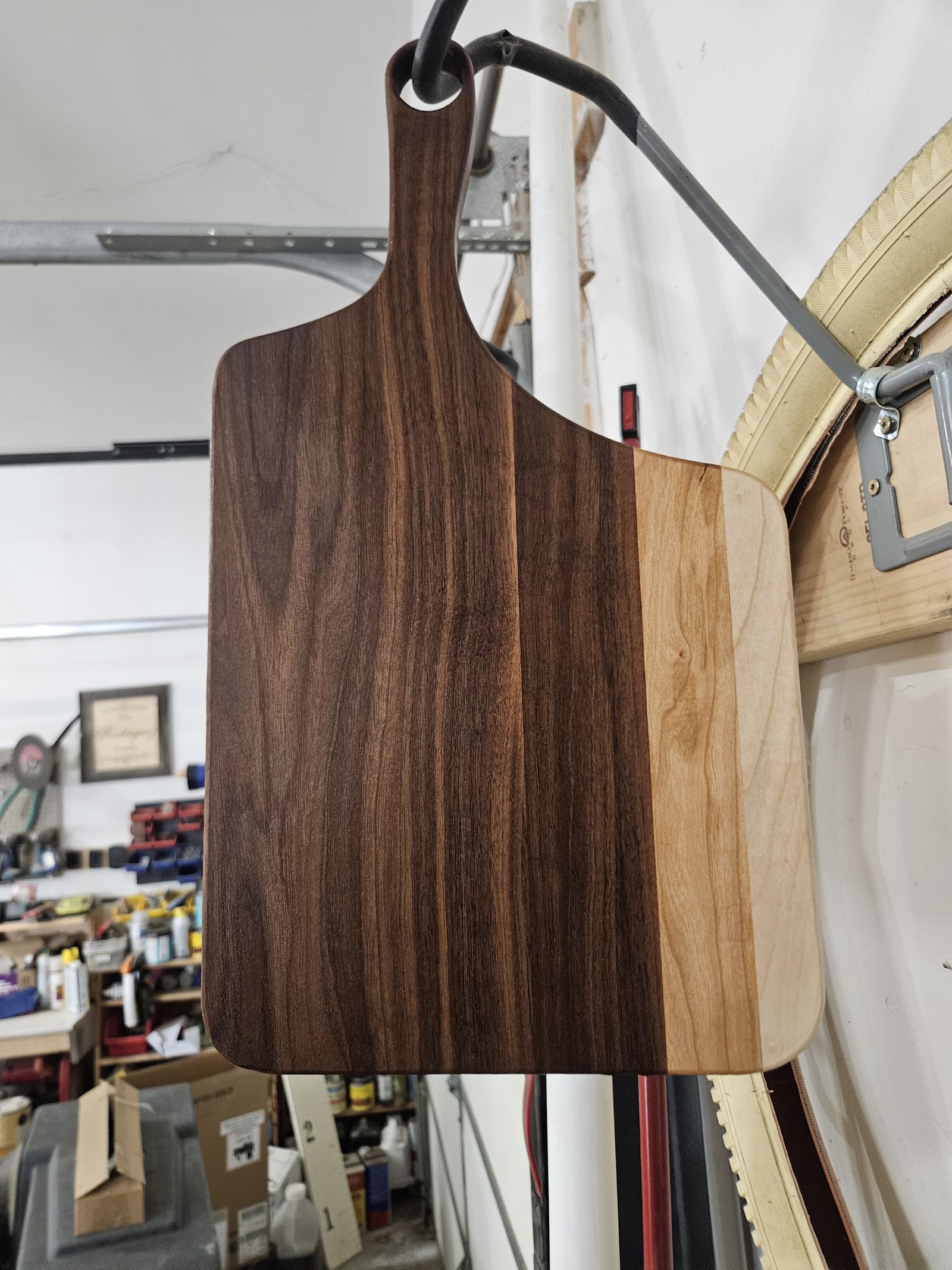 Walnut paddle cutting board hanging in the shop