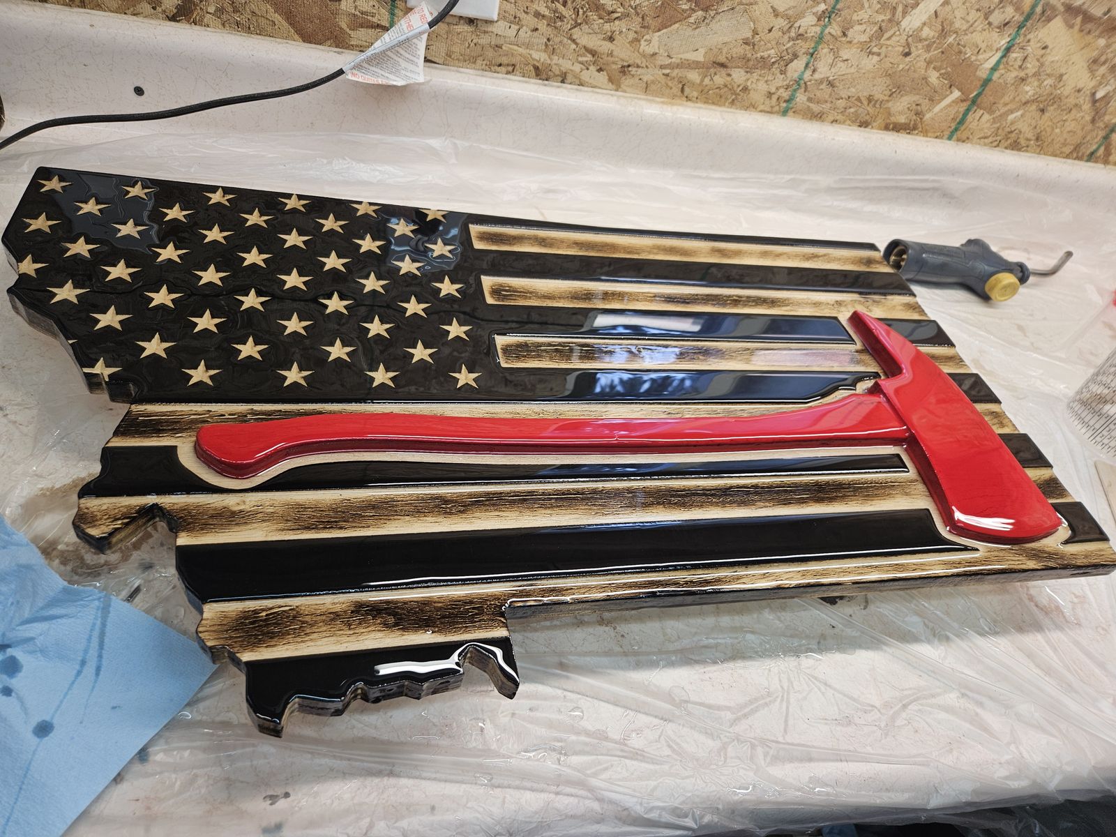 Montana-shaped wooden flag with a red firefighter axe, on the workbench