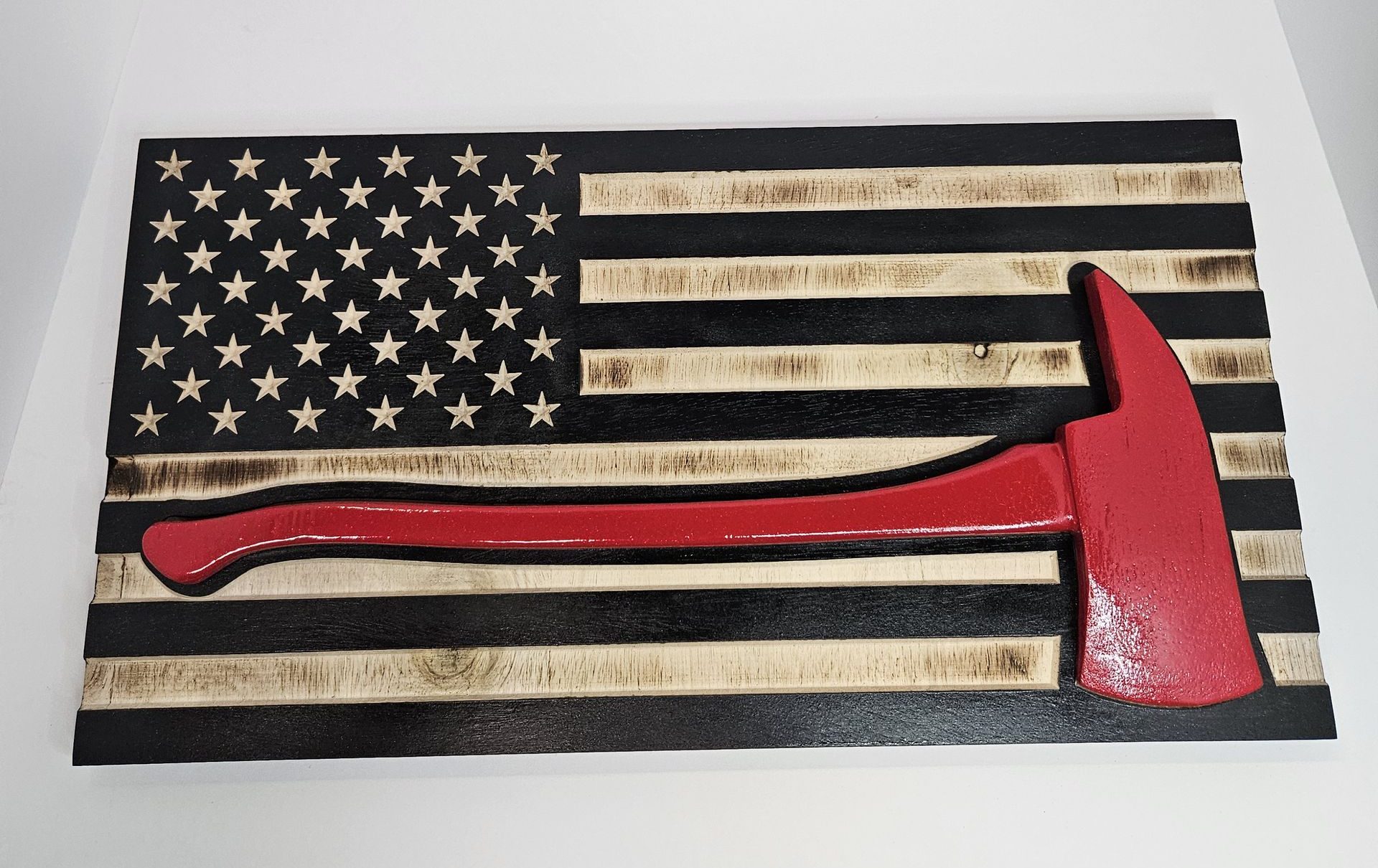 Carved wooden firefighter flag with red axe inlay in a photo box