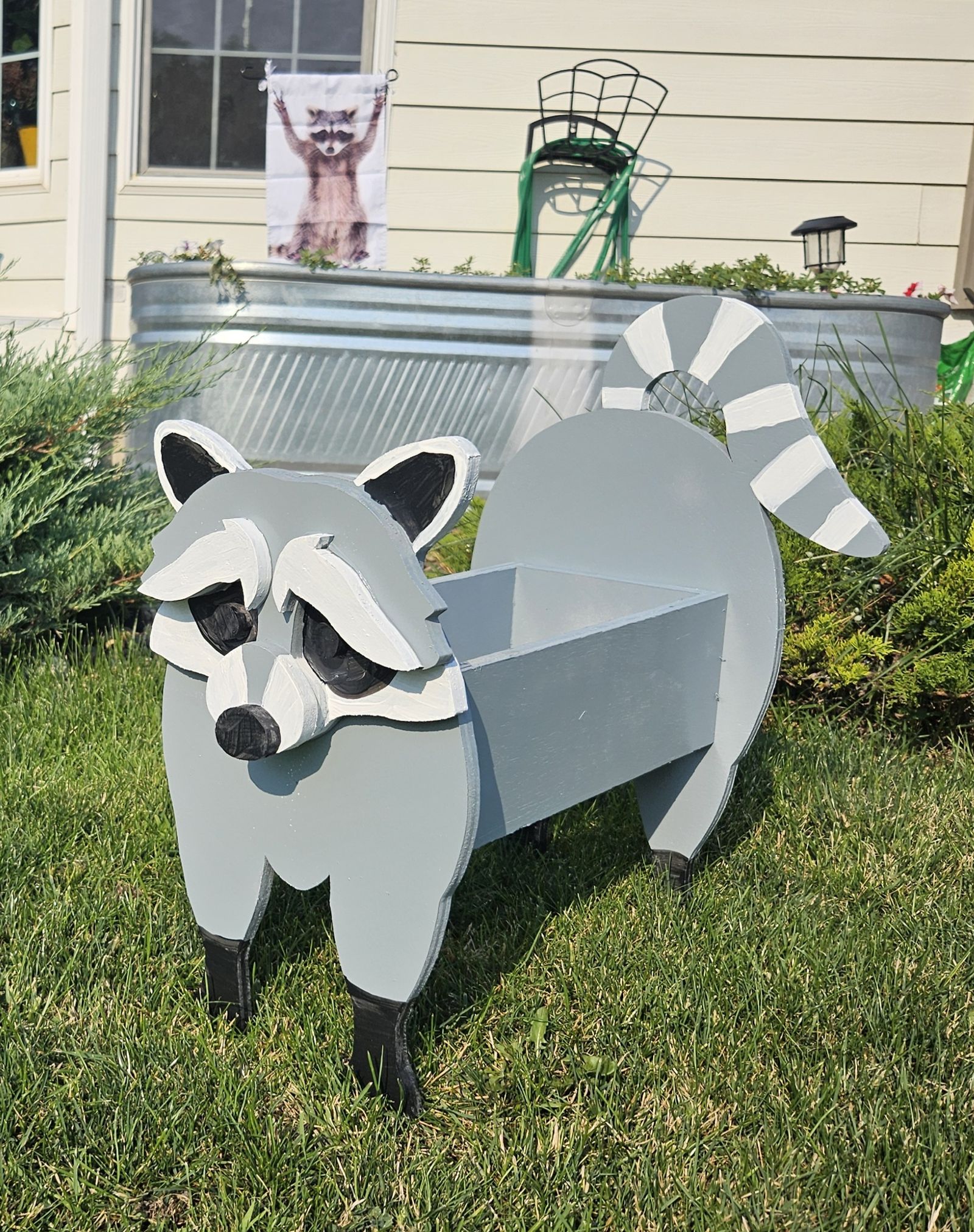 Wooden raccoon planter standing in a yard