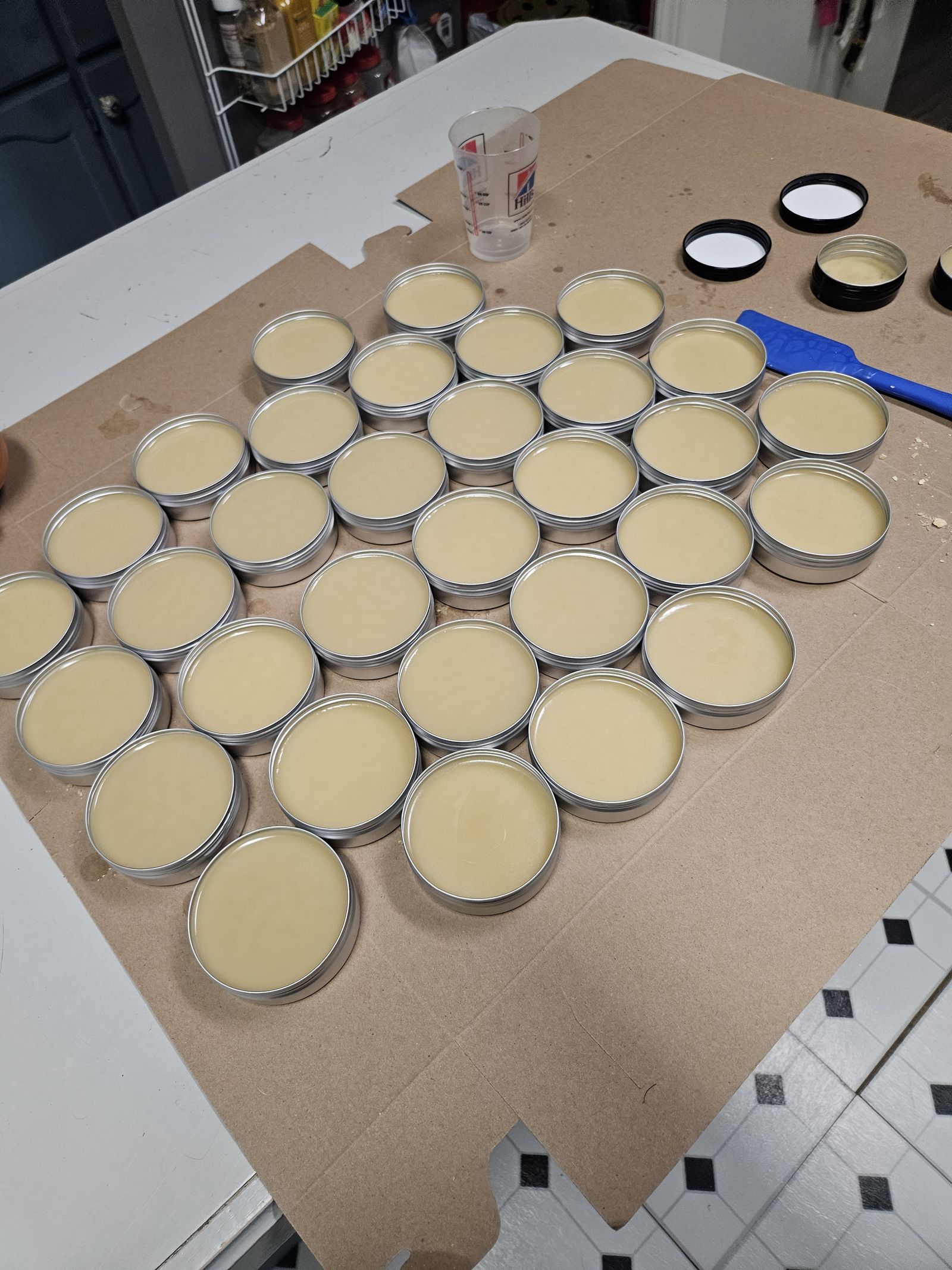 Fresh tins of wood wax laid out on cardboard in the shop